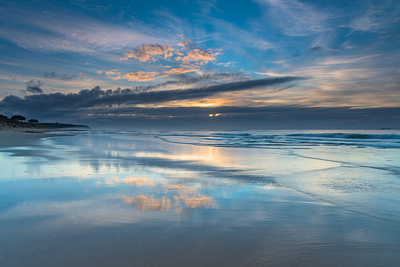 Sunrise Seascape with Clouds and Reflections on the Beach