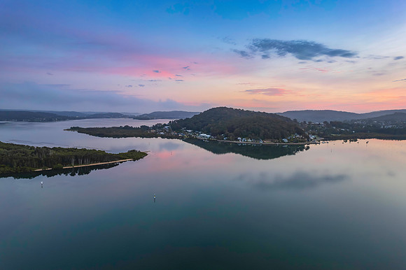 Soft and peaceful sunrise aerial waterscape with clouds and refl