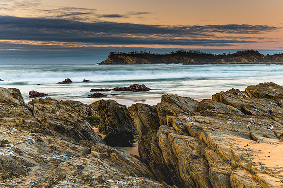 Sunrise at the beach with rocks and low cloud bank