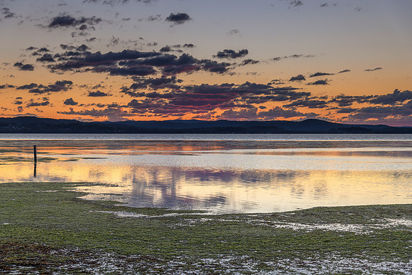 Sunset lights up the clouds in pink and purple over the Lake