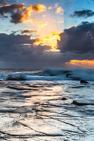 Moody sunrise seascape with clouds and sunrays at the rocky inle