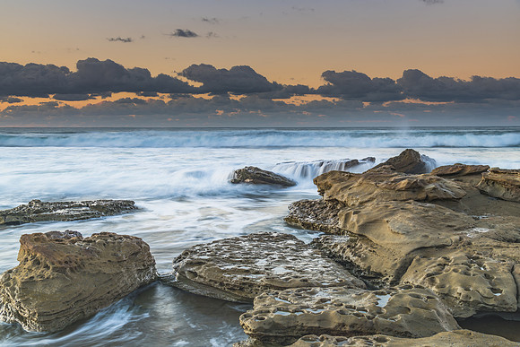 Sunrise Seascape with a low cloud bank and rocks
