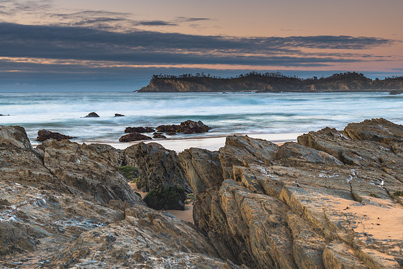 Sunrise seascape with rocks and low cloud bank