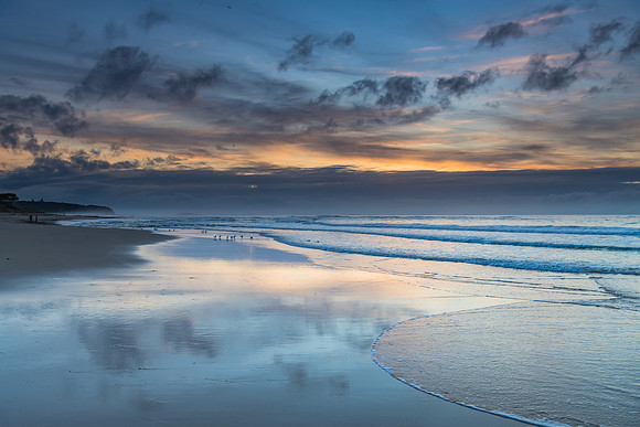 Sunrise seascape with cloud reflections on the beach
