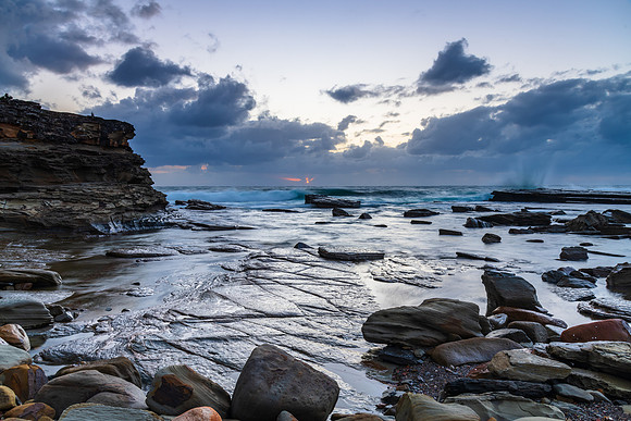 Moody sunrise seascape with clouds at the rocky inlet