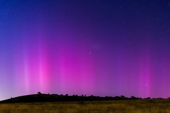 Aurora Australis display lights up the predawn sky in pinks