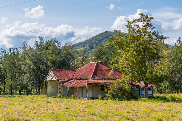 Abandoned farm house with red corrugated iron roof