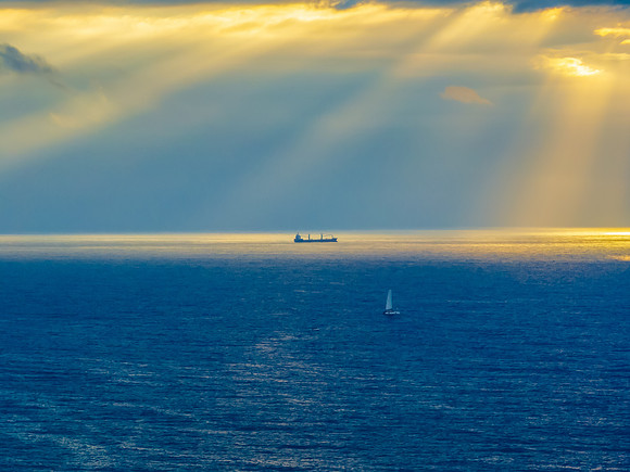 Sunrise Seascape with sunrays in the cloud covered sky and ship