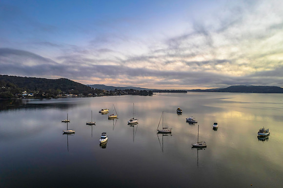 Sunrise waterscape with boats, soft clouds and reflections