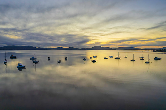 Sunrise waterscape with boats, soft clouds and reflections