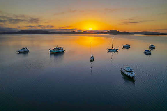 Sunrise waterscape with boats, soft clouds and reflections