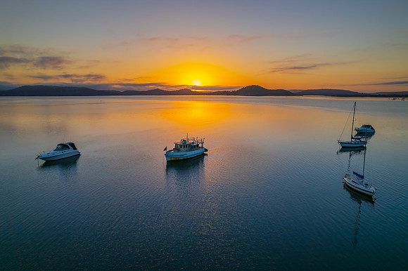 Sunrise waterscape with boats, soft clouds and reflections