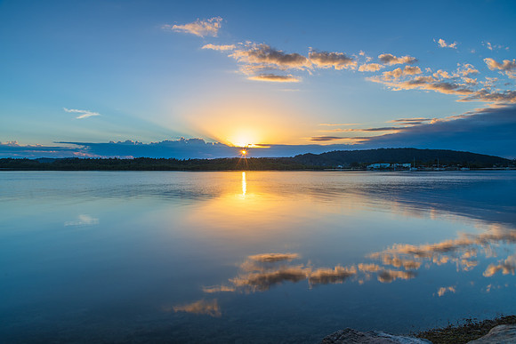 Sunrise waterscape with cloud reflections and sun rays