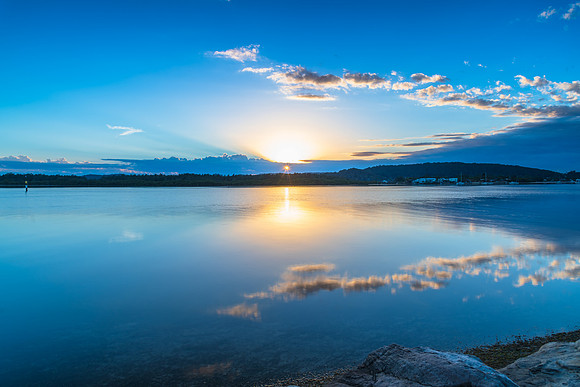 Sunrise waterscape with cloud reflections and sun rays
