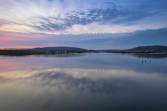 Soft and peaceful sunrise aerial waterscape with clouds and refl