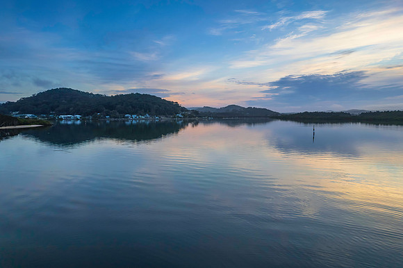 Soft and peaceful sunrise aerial waterscape with clouds and refl