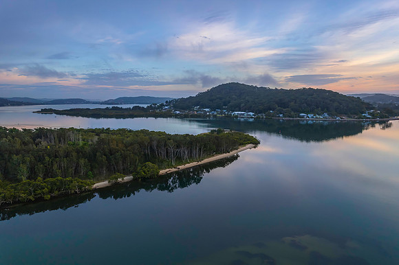 Soft and peaceful sunrise aerial waterscape with clouds and refl