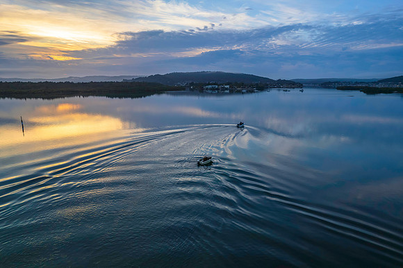 Soft and peaceful sunrise aerial waterscape with clouds and refl