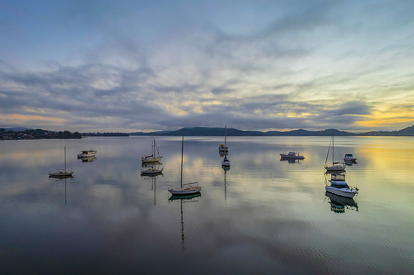 Sunrise waterscape with boats, soft clouds and reflections