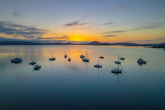 Sunrise waterscape with boats, soft clouds and reflections