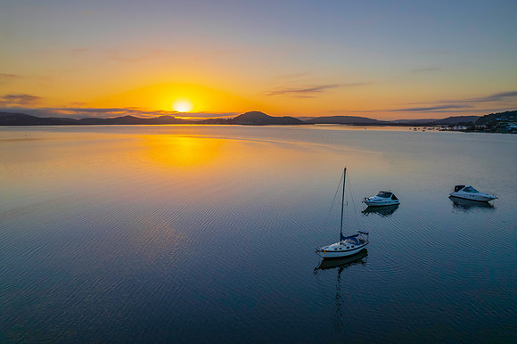 Sunrise waterscape with boats, soft clouds and reflections