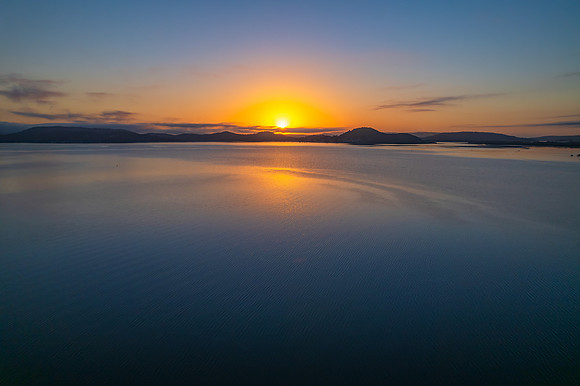 Sunrise waterscape with boats, soft clouds and reflections