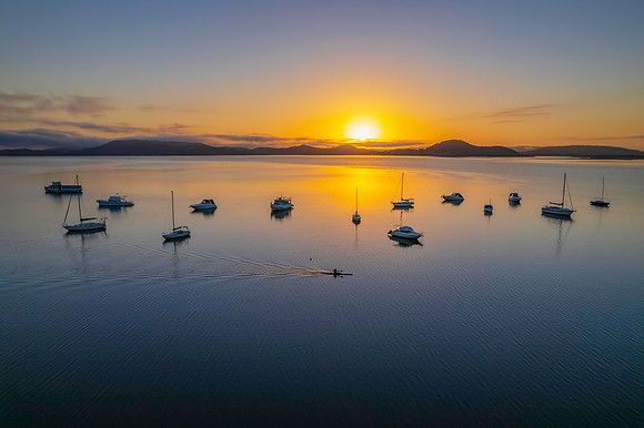Sunrise waterscape with boats, soft clouds and reflections