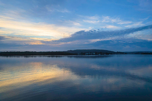 Soft and peaceful sunrise aerial waterscape with clouds and refl