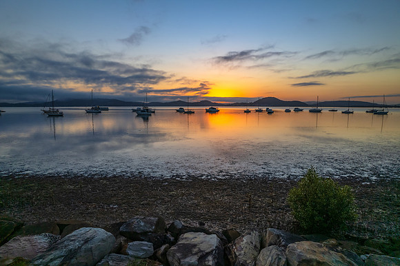 Sunrise waterscape with boats, soft clouds and reflections