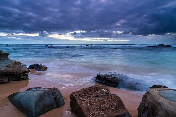 Moody morning bay seascape with rain clouds and rocks