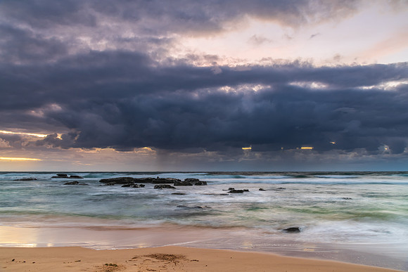 Moody morning bay seascape with rain clouds and rocks
