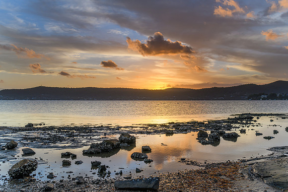 High cloud sunset waterscape with reflections by the bay