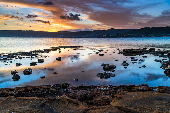 High cloud sunset waterscape with reflections by the bay