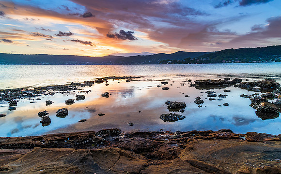 High cloud sunset waterscape with reflections by the bay