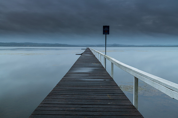 Rainy day sunrise waterscape with wharf