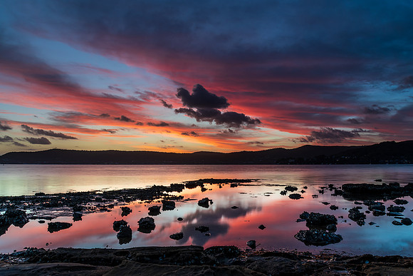 High cloud sunset waterscape with reflections by the bay