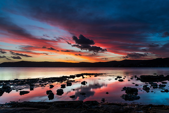 High cloud sunset waterscape with reflections by the bay