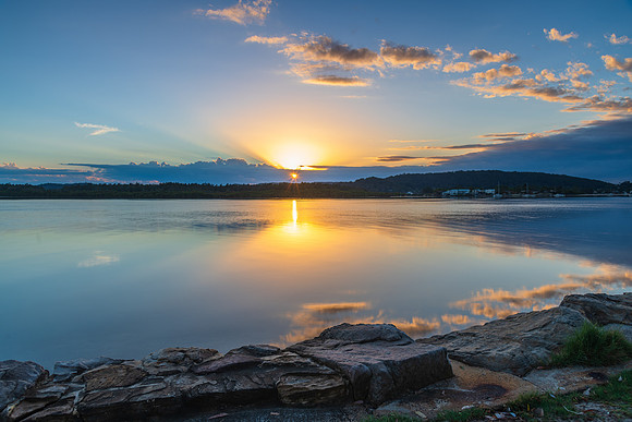 Sunrise waterscape with cloud reflections and sun rays