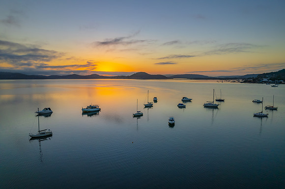 Sunrise waterscape with boats, soft clouds and reflections