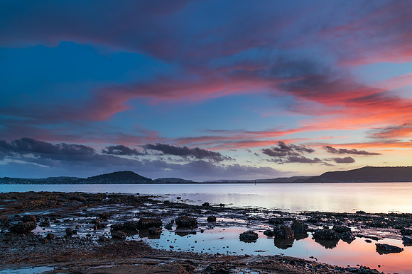 High cloud sunset waterscape with reflections by the bay