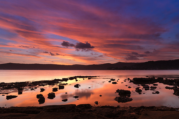 High cloud sunset waterscape with reflections by the bay
