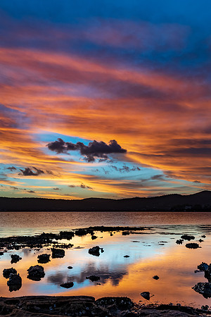 High cloud sunset waterscape with reflections by the bay