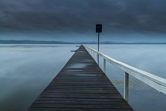 Rainy day sunrise waterscape with wharf