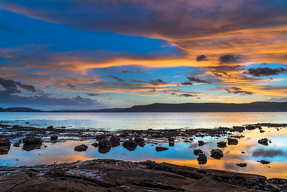 High cloud sunset waterscape with reflections by the bay