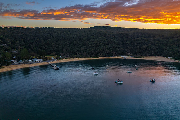 Peaceful sunrise over the bay with boats and mountain