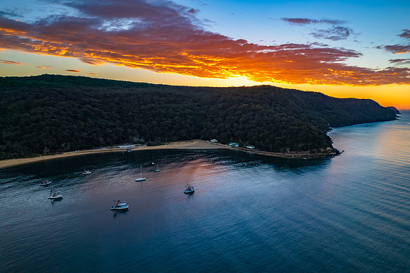 Peaceful sunrise over the bay with boats and mountain