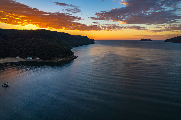 Peaceful sunrise over the bay with boats and mountain