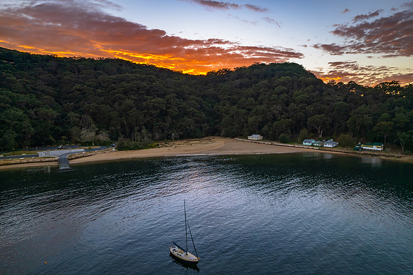 Peaceful sunrise over the bay with boats and mountain
