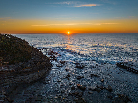 Sunrise over the calm sea and rocky Inlet