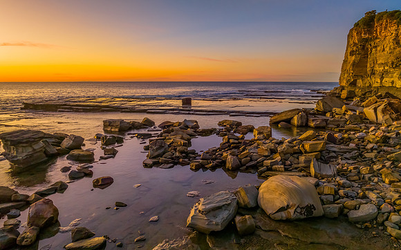 Sunrise over the calm sea and rocky Inlet